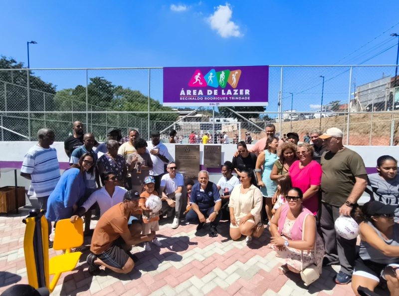 Vereador Julio Mariano posa com populares na inauguração da área de lazer no Jardim Brasília. Ao fundo, placa com nome do espaço e homenagens.