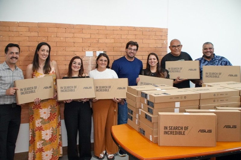 Autoridades e servidores posam com caixas de notebooks ASUS, sinalizando a entrega de novos equipamentos para as escolas de São Roque.