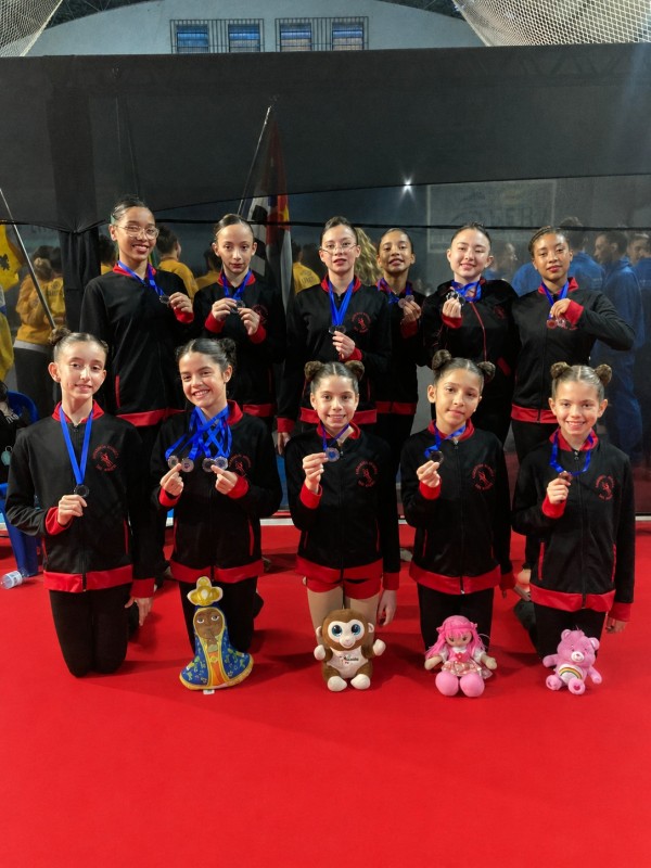 Atletas de ginástica rítmica de São Roque exibem medalhas conquistadas na Copa Roberta Gaio. O grupo posa com sorrisos e seus uniformes esportivos.