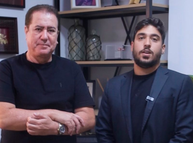 Vereador Diego Costa e outro homem posam para foto. Ao fundo, prateleiras com objetos decorativos.