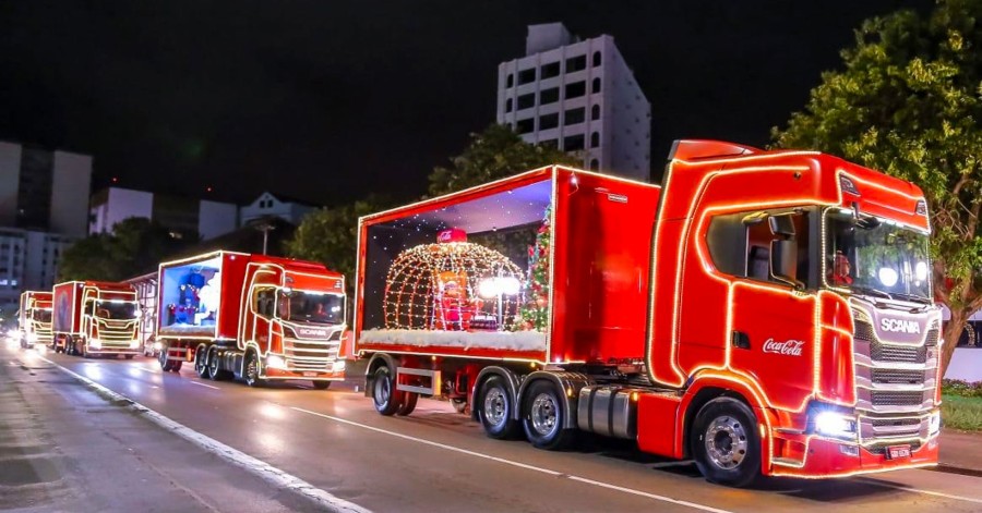 Caminhões iluminados da Caravana de Natal Coca-Cola desfilam pelas ruas de São Roque em clima festivo.