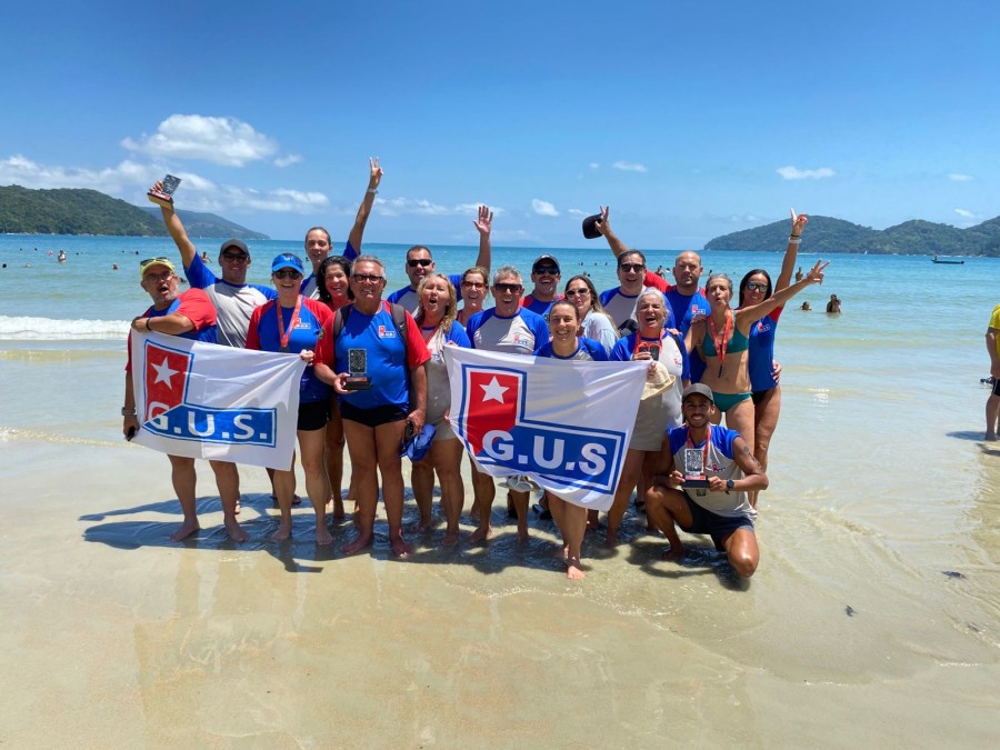 Atletas do Grêmio União Sanroquense competindo na 5ª etapa do Circuito Mares 2025 na Praia da Enseada, Ubatuba-SP.